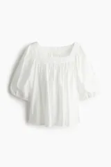Blusa corta blanca de tejido liviano con escote cuadrado fruncido, corte holgado, manga globo raglán al codo y elástico fino en los puños.