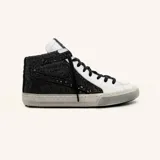 Zapatillas de caña alta de cuero vacuno blanco con glitter negro en los laterales y estrella de cuero negro. El interior es de cuero y la suela de caucho cosida.