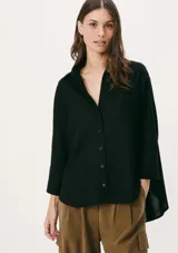 Camisa negra de corte holgado, con cuello clásico, cierre frontal con botones y mangas 3/4.