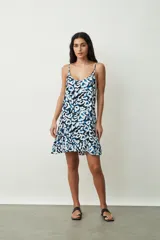 Vestido corto blanco de tirantes finos, con escote redondo y corte holgado tipo camisola, con un pequeño volante en el ruedo.