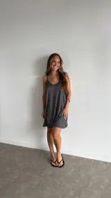 Vestido corto negro con estampado de lunares blancos, de corte holgado y tirantes finos.