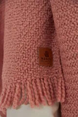 Ruana tejida color rosa claro con flecos en el borde.