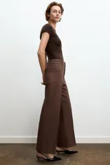 Jeans de tiro alto, pierna ancha y largo al tobillo, en denim celeste claro con efecto lavado. Presenta costura marcada en el centro de cada pierna y cierre frontal con cremallera y botón.