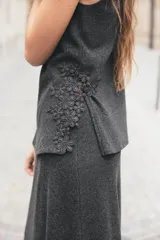 Top de punto canalé color gris oscuro, de cuello alto y sin mangas. Presenta apliques de encaje floral en los laterales del ruedo.