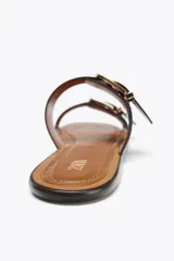 Sandalias planas color marrón con doble tira y hebillas doradas.