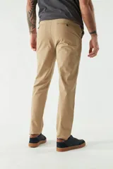 Pantalón chino color beige, de corte slim, con bolsillos laterales y traseros. Se ajusta a la cintura con cinturón de cuero marrón.
