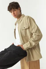 Sobrecamisa color beige de pana con cuello camisero, cierre frontal con botones, dos bolsillos de parche con botón en el pecho y bolsillos laterales.