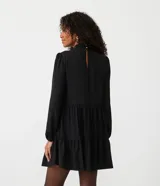 Vestido corto negro de chiffon con cuello alto, manga larga, volantes en la falda y cierre con botón en la espalda.