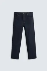 Jeans de corte slim fit confeccionados en denim de algodón sin lavados, color azul oscuro. Cierre frontal con botones y cinco bolsillos.