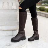 Bota de caña alta color marrón chocolate, confeccionada en cuero vacuno. Tiene suela de goma sport artesanal, cierre YKK del lado interno y horma de punta redonda.