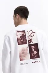 Buzo blanco de algodón con cuello redondo, puños y bolsillos laterales. Presenta un estampado en la espalda con cuatro imágenes de plantas en tonos sepia y texto.