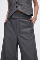 Pantalón gris de poliéster, corte ancho y tiro alto, con bolsillos laterales.