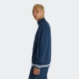 Campera deportiva New Balance de tejido piqué de punto doble, color azul marino, con cierre frontal y cuello alto. Presenta puños y dobladillo con franjas horizontales blancas. Incluye un parche con el logo NB en el pecho y un tirador de insignia NB en el cierre.
