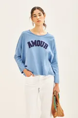 Sweater celeste de viscosa, poliéster y poliamida, de corte holgado y manga larga. Tiene bordado en buclé con la palabra 'Amour' en el frente.