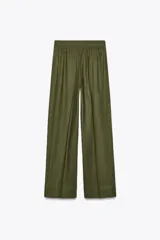 Pantalón color beige de lino, de tiro alto con cintura elástica, bolsillos laterales ocultos en costura y pernera ancha.