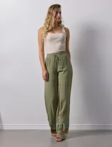 Pantalón verde oliva de rayón con cintura elastizada tipo smock y bordados florales en los bajos.