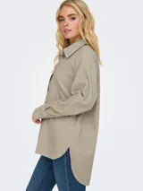 Camisa de pana color beige con cuello clásico, mangas largas y puños con botones. Corte holgado.