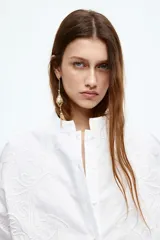 Camisa blanca de algodón con cuello mao, bordado floral tono sobre tono y cierre de botones. Tiene corte holgado, hombros caídos, mangas largas con abertura en los puños y bajo recto.