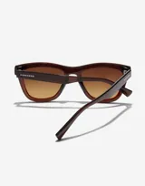 Lentes de sol Hawkers modelo Downtown Max, unisex, con montura cuadrada color marrón y lentes degradadas en tonos marrón y amarillo.