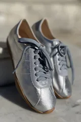 Zapatillas bajas con estampado animal print en blanco, marrón y negro, con puntera y talón en cuero color crema y suela de goma color caramelo.
