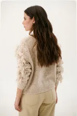 Sweater color arena de tejido de punto con cuello redondo y mangas largas con flecos.