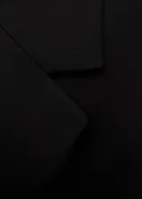 Abrigo largo negro con cuello de pico con solapa, hombros pronunciados, cierre de botones en la parte delantera y dos bolsillos de solapa laterales.