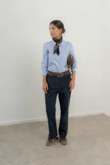 Pantalón de jean azul oscuro de corte recto con detalle de botones dorados en el tobillo.