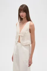 Chaleco color crudo sin mangas con escote en V y lazo de ajuste en el frente.