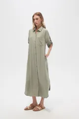 Vestido camisero midi negro de corte holgado, con cuello camisero, mangas cortas con trabillas, cierre frontal con botones, bolsillo en el pecho y bolsillos laterales.