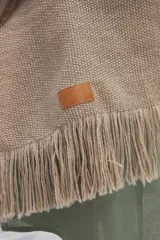 Chal de tejido liviano confeccionado en lana 100% sin teñir, color marrón, con detalle de flecos en los extremos.
