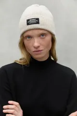 Gorro de lana reciclada color gris, con diseño acanalado y etiqueta en la parte frontal.