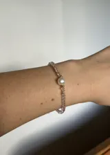 Pulsera elástica con cuentas facetadas de cristal rosa, detalles de acero dorado y una perla barroca de río.