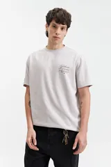 Remera de manga corta color verde claro con estampado de texto en el pecho, de corte oversize y cuello redondo.