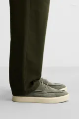 Zapato náutico de cuero color azul marino con cordones finos y suela plana.