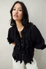 Camisa negra de tencel liviana con volados románticos y manga corta.