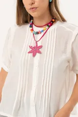 Blusa blanca de mangas cortas con cuello redondo y abotonadura frontal.