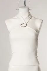 Top blanco de estilo halter con aro metálico en el cuello.