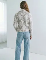 Buzo de tejido de punto con cuello vuelto que se ajusta con botones. Presenta un diseño jacquard en tonos blanco, gris y rosado pálido.