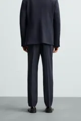 Pantalón de vestir azul marino, de corte slim fit, confeccionado en tejido con 17% de lana. Cuenta con bolsillos frontales y traseros de doble vivo con botón. Cierre frontal con cremallera y botón.
