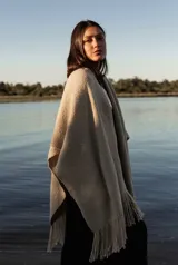 Ruana color beige confeccionada en lana merino con flecos en el borde inferior.