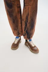 Zapatillas deportivas negras con detalles en blanco y suela color caramelo.