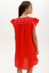 Vestido corto celeste de lino, corte suelto, con cuello redondo con volados y lazo, mangas cortas con volados.