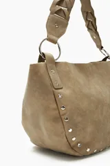 Cartera beige con tachas plateadas, doble asa de hombro con detalle trenzado y herrajes metálicos.