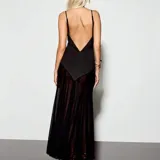 Vestido largo negro con escote en V profundo, tirantes finos, paneles transparentes en el abdomen y la falda, y detalles de tela en forma de picos en la parte delantera.