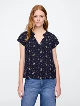 Blusa blanca de manga corta con escote en V y detalle de volados en el cuello.