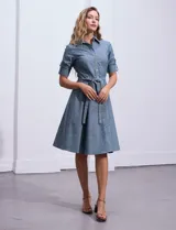 Vestido camisero blanco de algodón con cuello con solapa, delantera abotonada, mangas 3/4 regulables con presilla y botón, y cintura con lazo de ajuste.