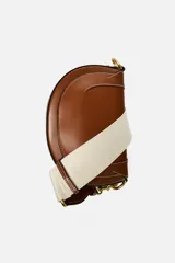 Bolso de hombro ovalado color negro, con asa de doble tira redonda con detalles metalizados dorados. Cierre imantado y asa de bandolera extraíble con tejido a contraste. Bolso interior con cierre mediante cremallera metálica.