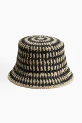 Sombrero tipo bucket de paja trenzada en colores beige y negro, con diseño calado.