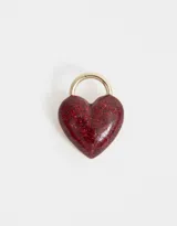 Pin prendedor con forma de corazón cubierto de glitter rojo y aro dorado.