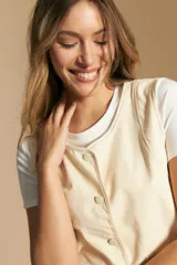 Chaleco negro de vestir con cuello solapa y cierre frontal de botones. Presenta costuras contrastantes blancas que definen el diseño y bolsillos delanteros. Se combina con una camisa blanca de manga larga.